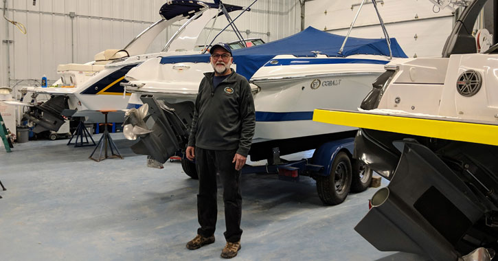 man standing in front of boats in a warehouse