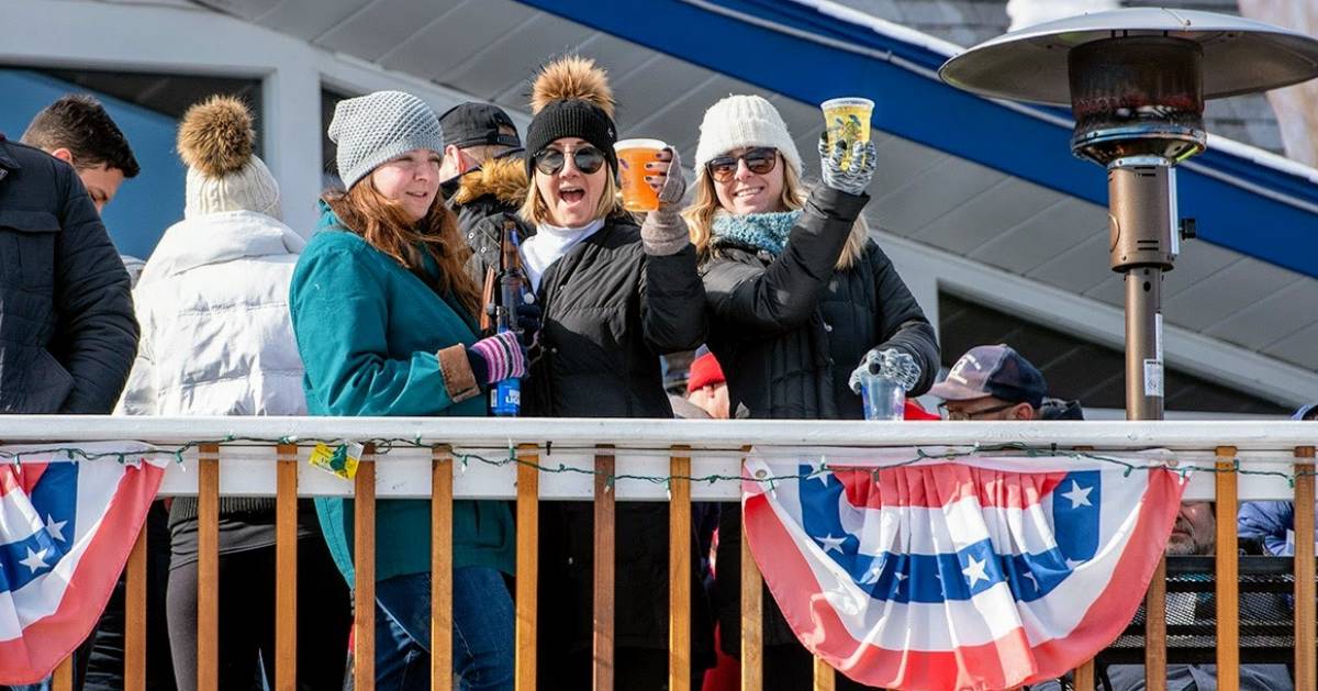 women on balcony cheersing with drinks in winter