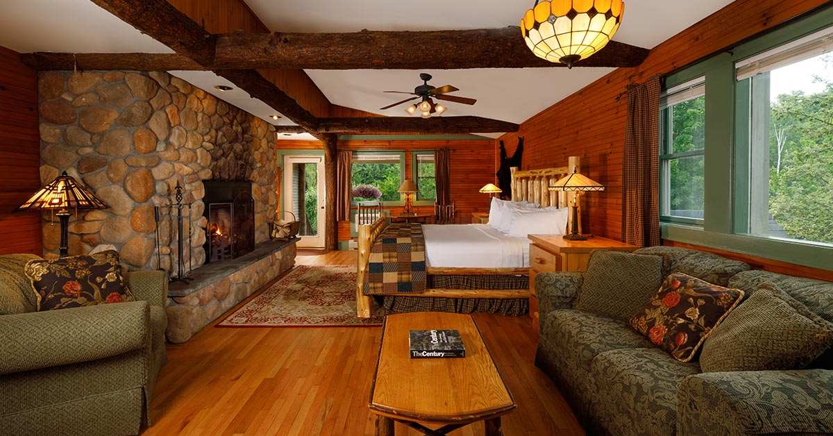 a spacious and rustic hotel room with a bed, stone fireplace, and other furniture