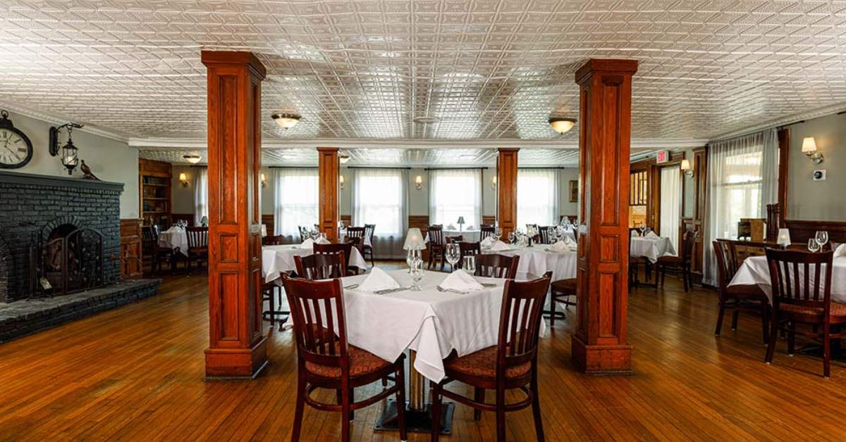 a spacious restaurant dining room with a fireplace, wooden posts, and tables spread out around the room