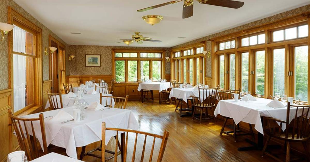 a dining room with lots of winds and tables with white tablecloths