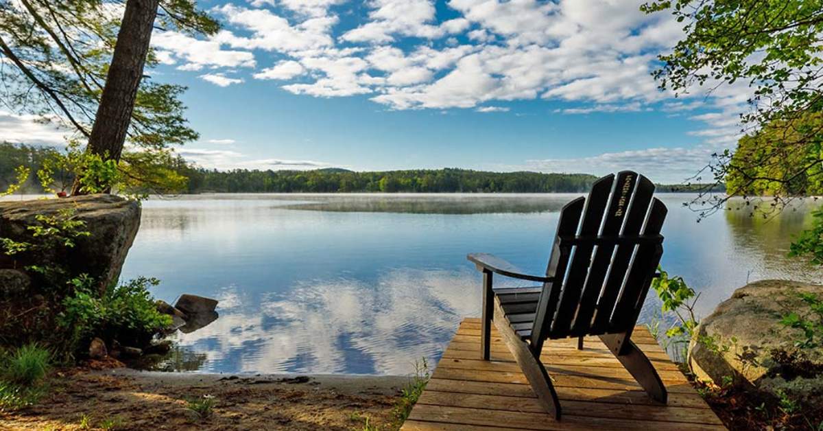 an adirondack chair on a boat dock by a lake