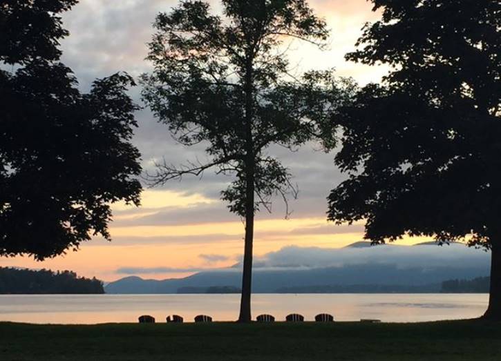 Pastel sunrise over lake with silhouettes of trees