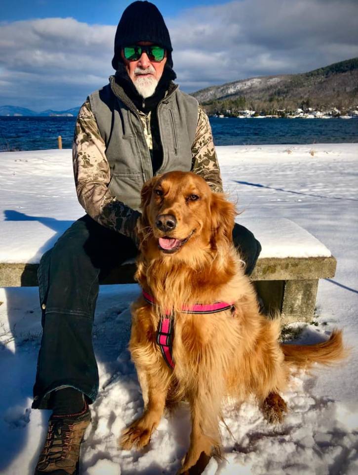 man with dog in front of lake in winter