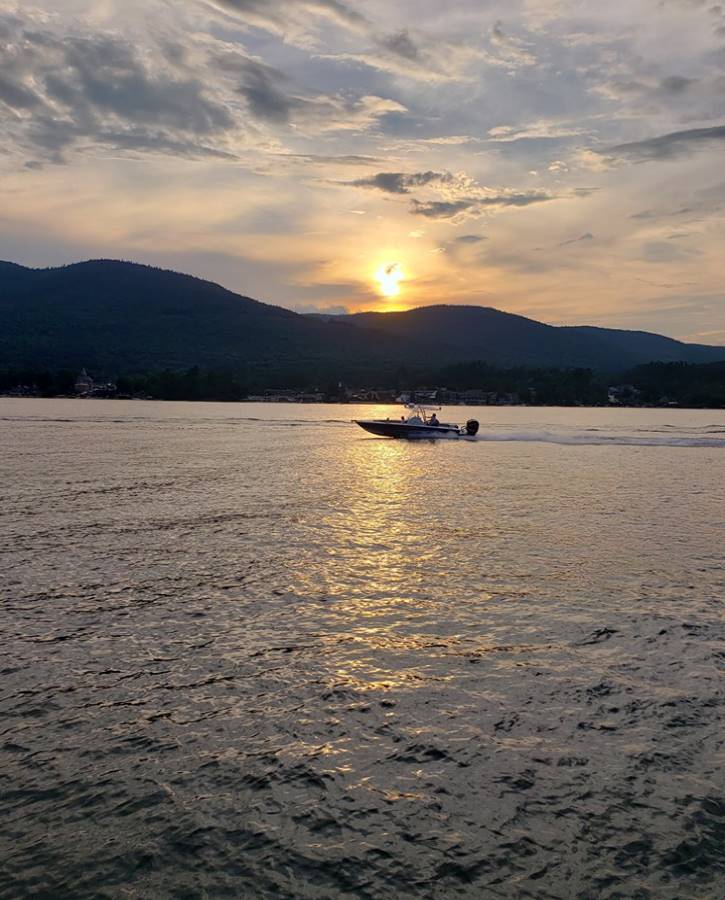 Sunset over lake with mountains and a single boat