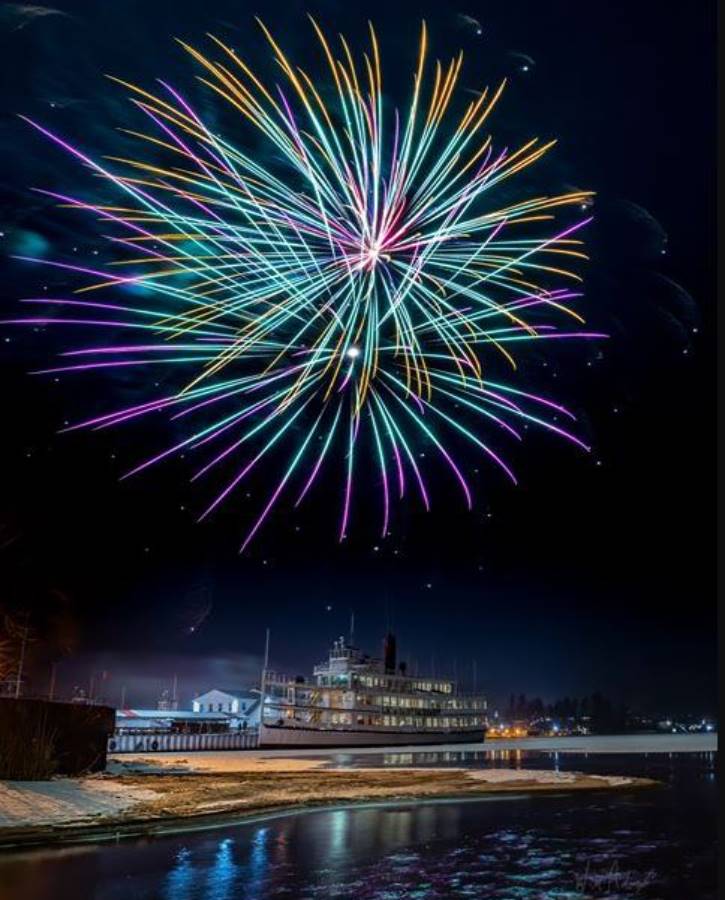 Colorful fireworks over steamboat on icy lake