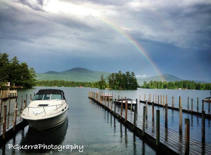 Rainbow over lake on a cloudy day with a dock