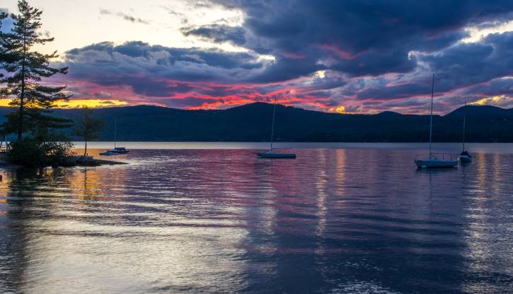 Colorful cloudy sky over lake with four sailboats