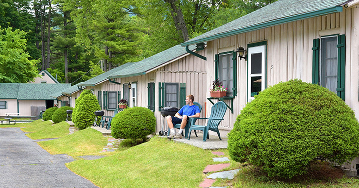 man in chair in front of cabin