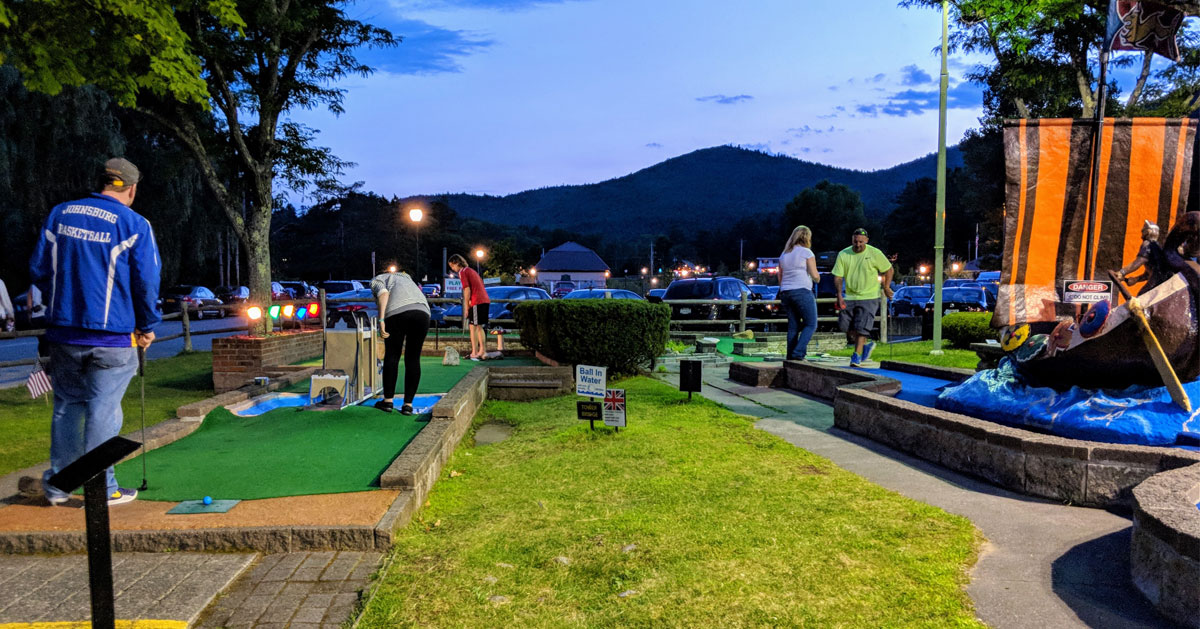 mini golf in progress at dusk, mountains in background