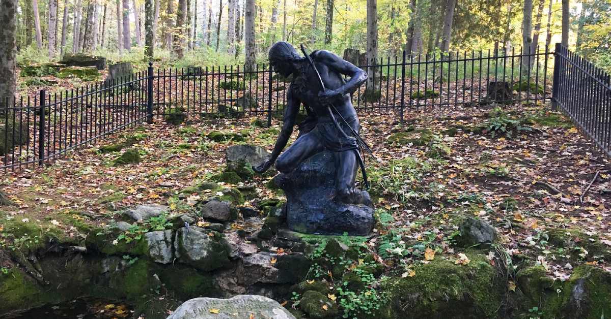 statue of mohawk warrior dipping his palm in the stream