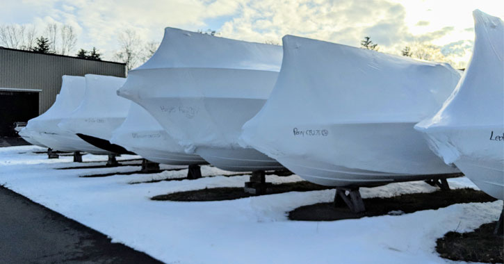 shrink wrapped boats outside next to a tractor