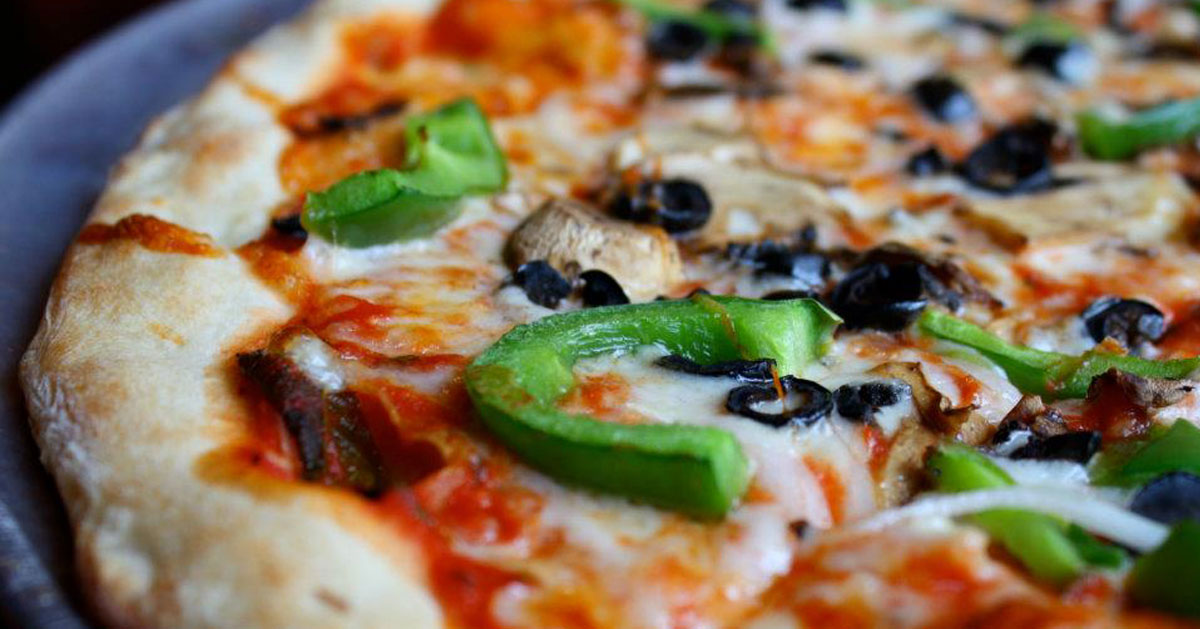 close up of pizza with green peppers and black olives