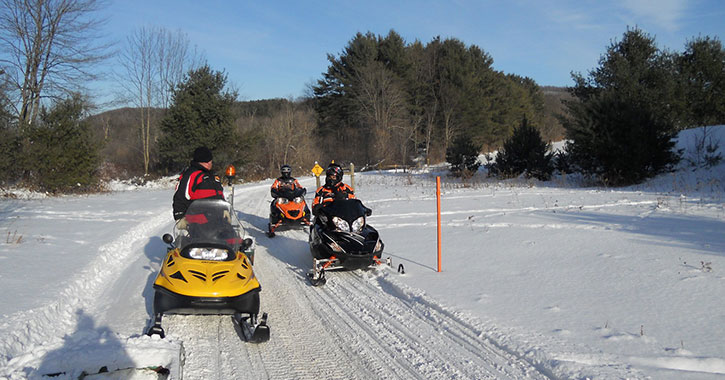 three snowmobilers on a trail