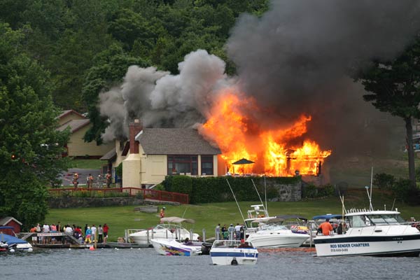 house on fire with gray smoke and people looking on