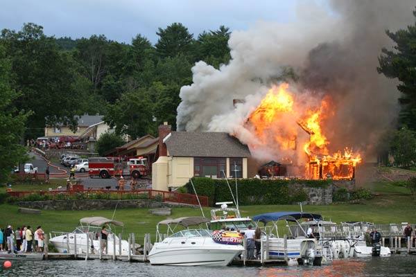 house on fire with gray smoke and people looking on