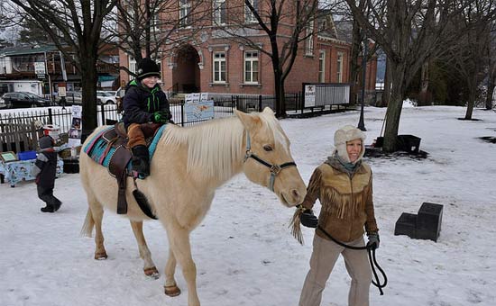 young boy riding horse at winter carnival